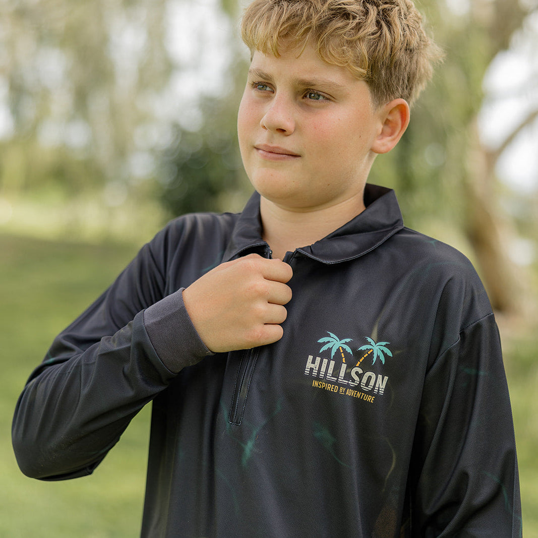 Young boy wearing a black shirt with 'Hillson' logo outdoors